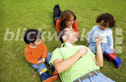 blickwinkel - Familie liegt im Park auf dem Rasen - family lying in a