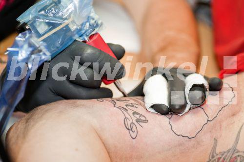 blickwinkel Oberarm wird taetowiert in einem Tattooladen tattooer