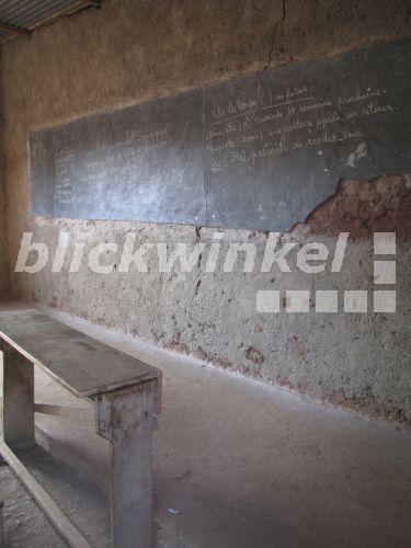 blickwinkel - primitives Klassenzimmer mit Holzbank vor schadhafter